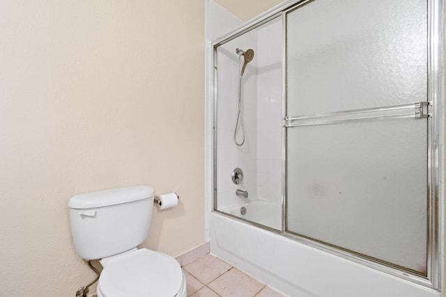 bathroom featuring toilet, shower / bath combination with glass door, and tile floors