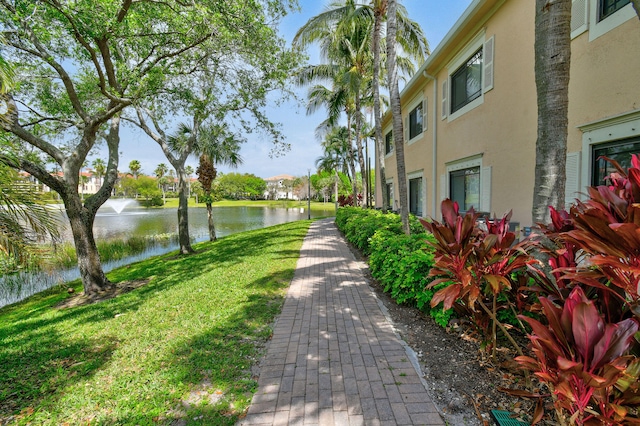 surrounding community with a water view and a lawn