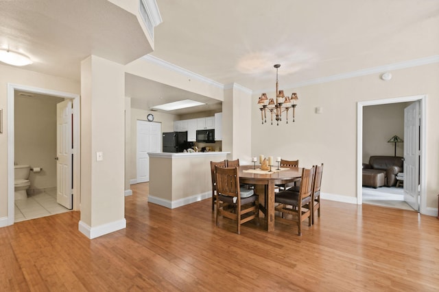 dining area with ornamental molding, a chandelier, and light wood-type flooring