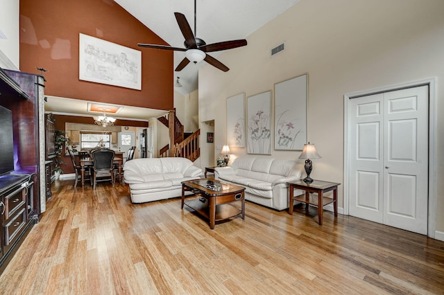 living room with high vaulted ceiling, wood-type flooring, and ceiling fan with notable chandelier