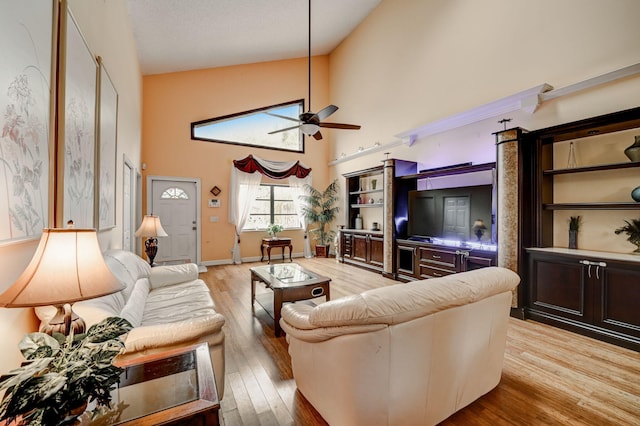 living room featuring high vaulted ceiling, ceiling fan, and light wood-type flooring