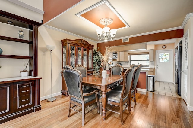 dining room with light hardwood / wood-style floors, ornamental molding, and a chandelier