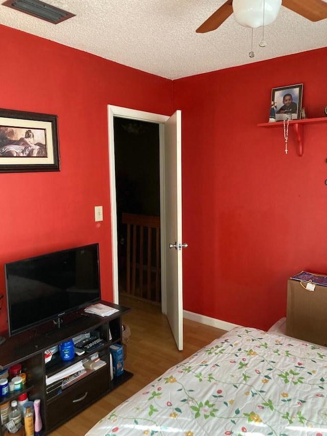 bedroom featuring a textured ceiling, ceiling fan, and hardwood / wood-style flooring