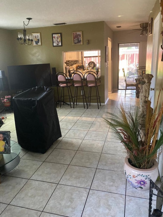 living room with light tile floors and ceiling fan with notable chandelier