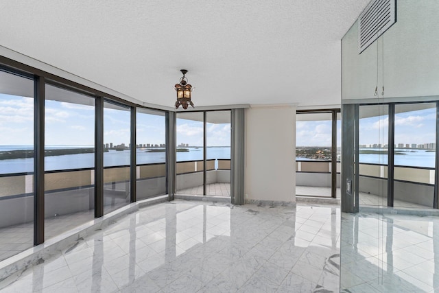 spare room with a water view, expansive windows, and a wealth of natural light