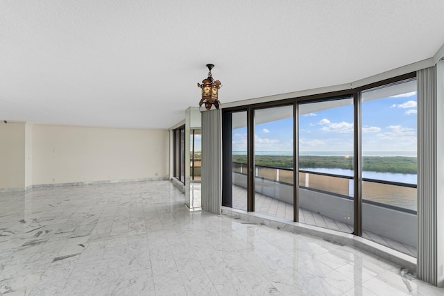 spare room featuring a water view, expansive windows, and a textured ceiling