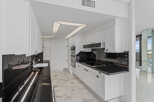 kitchen with decorative backsplash, black electric cooktop, sink, and white cabinetry