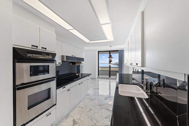 kitchen featuring black electric cooktop, stainless steel double oven, sink, and white cabinets