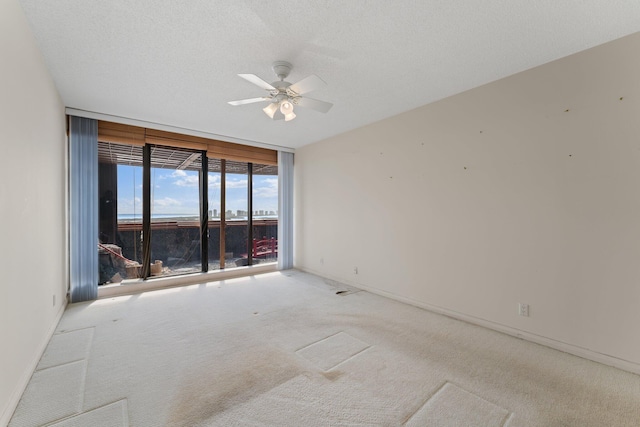 unfurnished room with light colored carpet, ceiling fan, and a textured ceiling