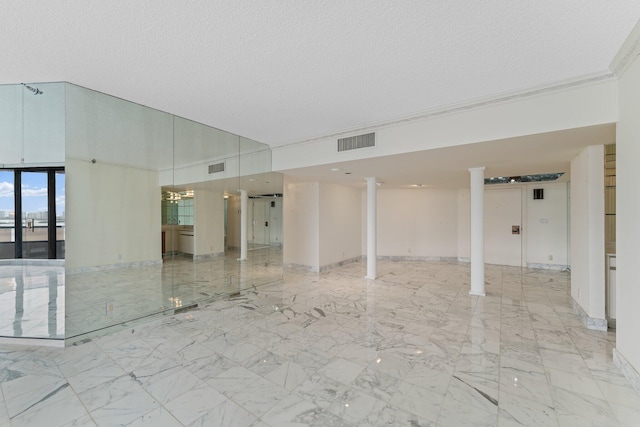 empty room featuring decorative columns and a textured ceiling