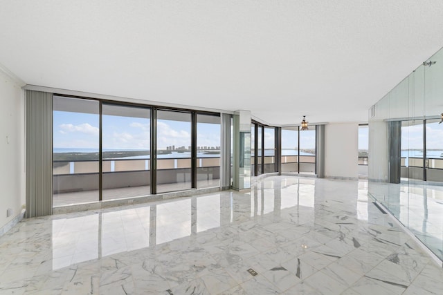 unfurnished room featuring a water view, a healthy amount of sunlight, floor to ceiling windows, and a textured ceiling