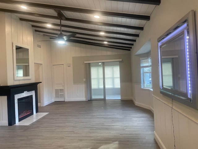 unfurnished living room featuring wood-type flooring, vaulted ceiling with beams, ceiling fan, and a premium fireplace