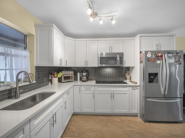 kitchen featuring stainless steel appliances, tasteful backsplash, rail lighting, sink, and light tile floors