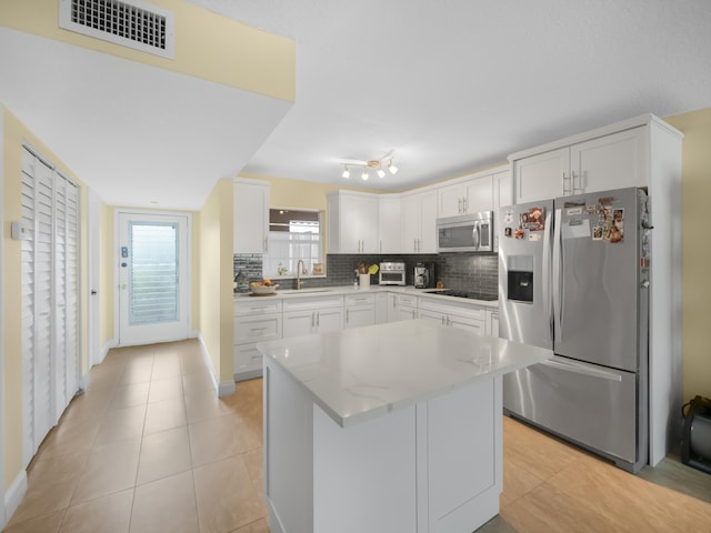 kitchen with appliances with stainless steel finishes, white cabinetry, sink, and tasteful backsplash