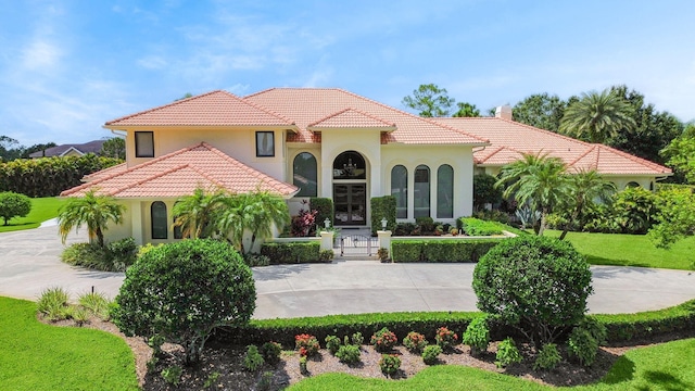 mediterranean / spanish-style house featuring stucco siding, a tiled roof, and a front lawn