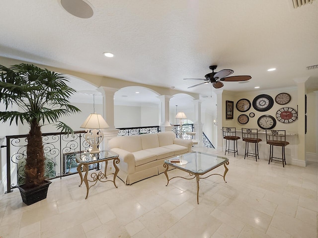 living area featuring a ceiling fan, visible vents, ornate columns, recessed lighting, and a textured ceiling