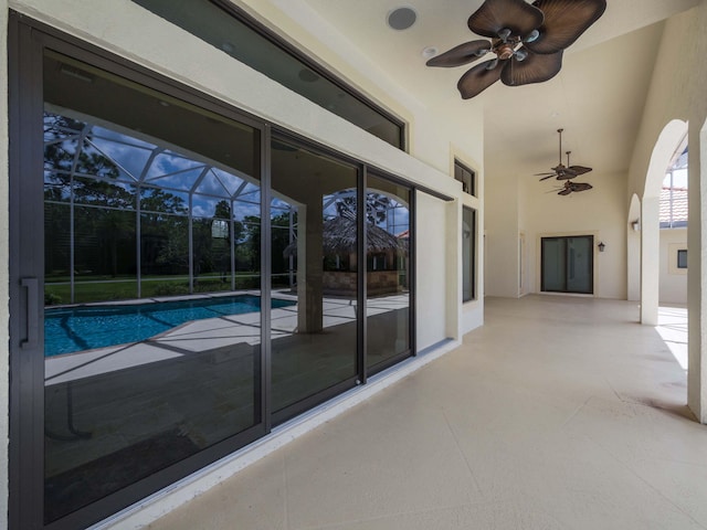 pool featuring glass enclosure, a patio area, and ceiling fan