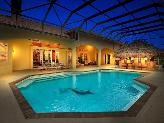 pool with outdoor dry bar, a patio area, and glass enclosure