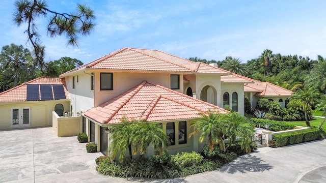 mediterranean / spanish-style home featuring stucco siding, concrete driveway, french doors, and a tile roof