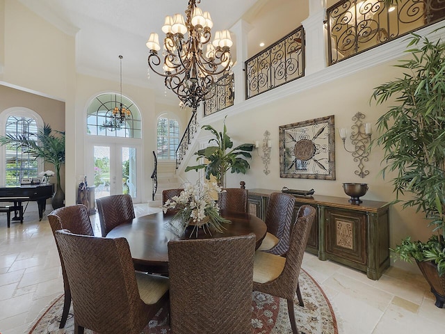 dining space featuring a chandelier, stairs, stone tile floors, french doors, and a towering ceiling