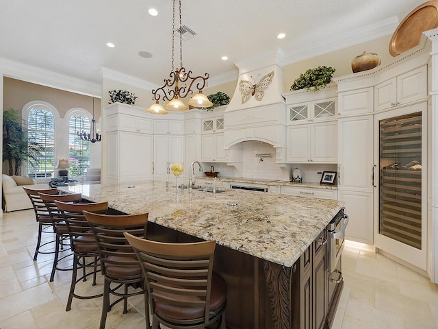 kitchen featuring tasteful backsplash, glass insert cabinets, crown molding, beverage cooler, and a sink