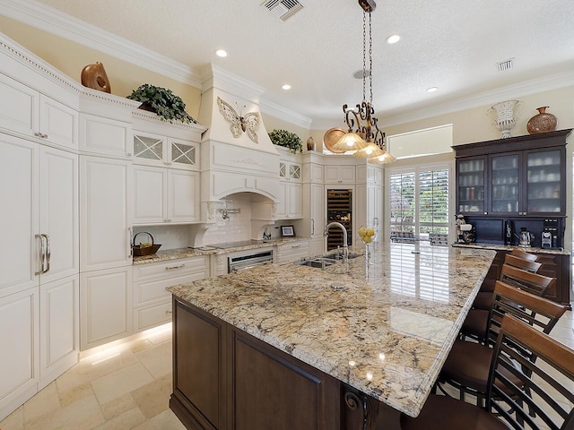 kitchen featuring visible vents, glass insert cabinets, ornamental molding, and decorative backsplash