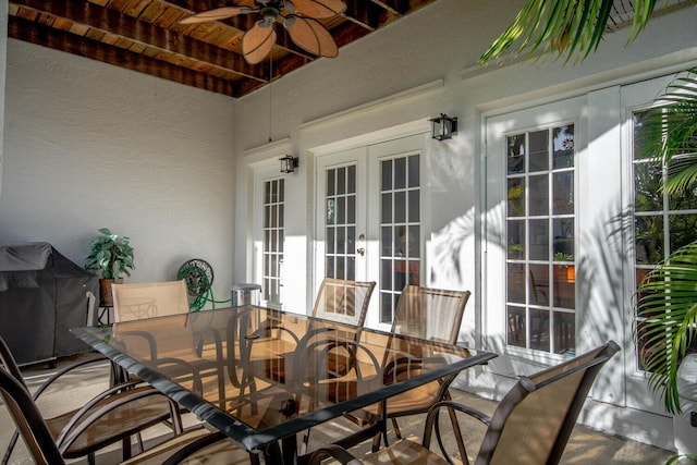 sunroom / solarium featuring beam ceiling, wooden ceiling, ceiling fan, and french doors