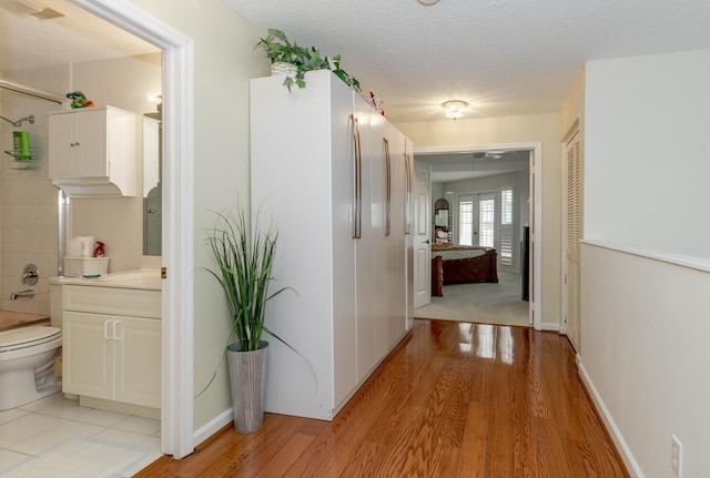 corridor with light hardwood / wood-style floors and a textured ceiling