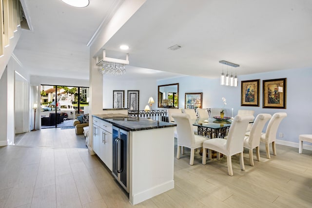 kitchen featuring decorative light fixtures, wine cooler, light hardwood / wood-style flooring, a notable chandelier, and white cabinetry