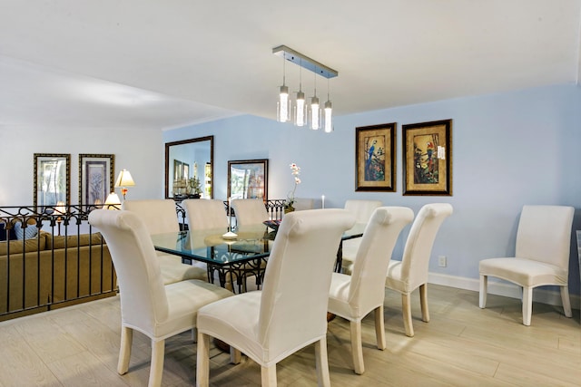 dining area with light wood-type flooring and a notable chandelier