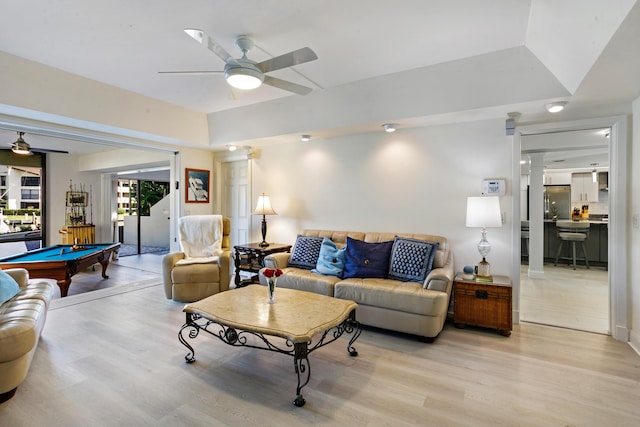 living room featuring light wood-type flooring, a raised ceiling, ceiling fan, and pool table