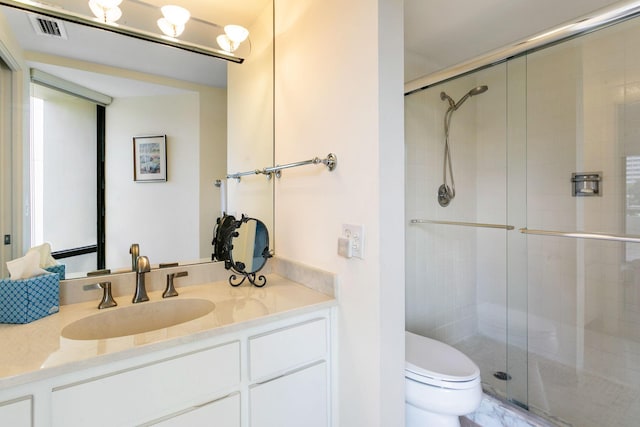 bathroom featuring vanity, toilet, and a shower with shower door