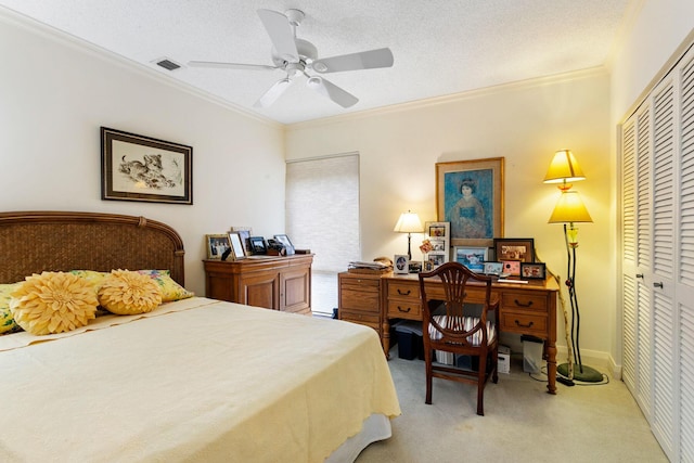 carpeted bedroom featuring a textured ceiling, a closet, ornamental molding, and ceiling fan