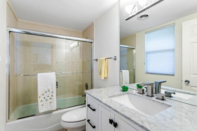 full bathroom featuring toilet, vanity, and combined bath / shower with glass door