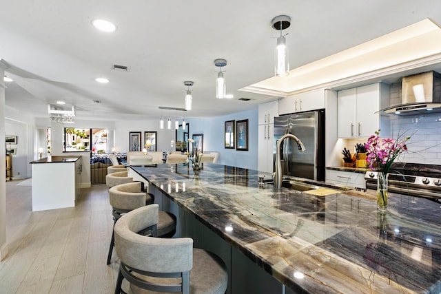 kitchen featuring decorative backsplash, dark stone counters, stainless steel appliances, decorative light fixtures, and white cabinets