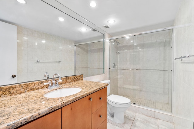 bathroom with tile patterned floors, vanity, toilet, and a shower with door