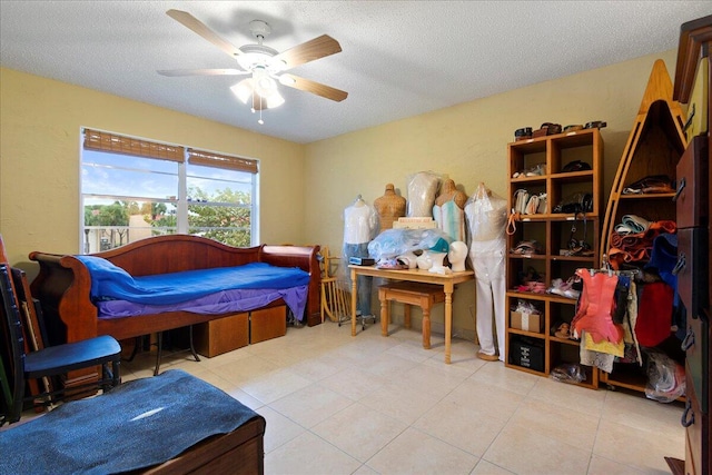 bedroom featuring ceiling fan, light tile patterned floors, and a textured ceiling