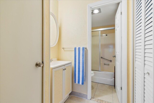 full bathroom with toilet, bath / shower combo with glass door, tile patterned floors, and vanity