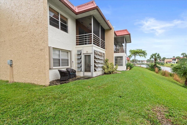 rear view of property featuring a sunroom and a lawn