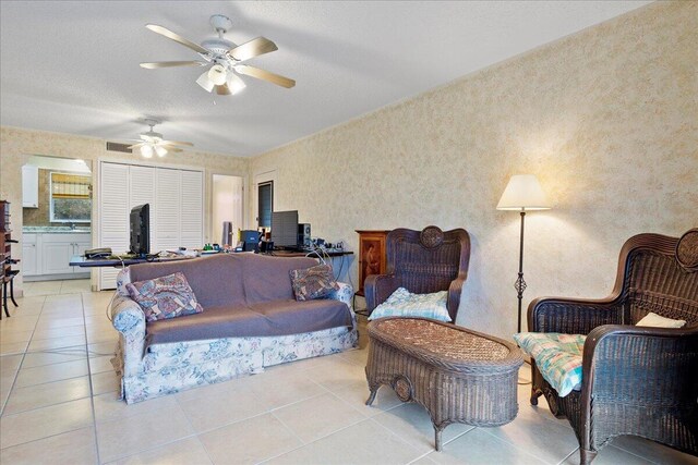 living room with a textured ceiling, ceiling fan, and light tile patterned floors