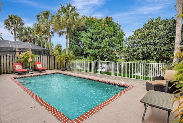 view of pool with a patio area, a water view, and a lanai