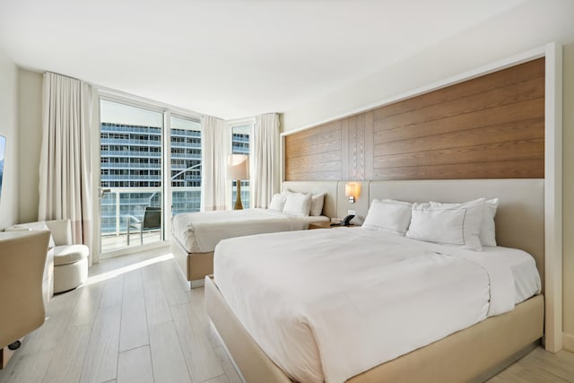 bedroom featuring access to outside, floor to ceiling windows, and light hardwood / wood-style flooring