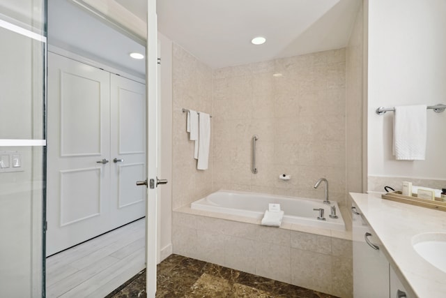 bathroom featuring vanity, tile flooring, and tiled tub