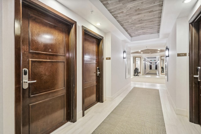 hall featuring a raised ceiling and light tile floors