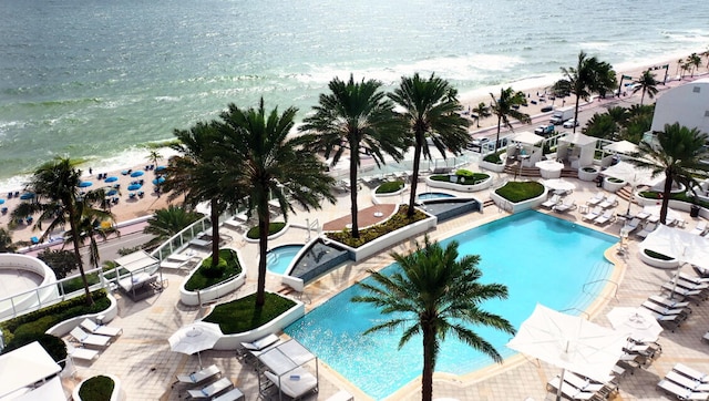 view of swimming pool featuring a patio area, a community hot tub, a view of the beach, and a water view