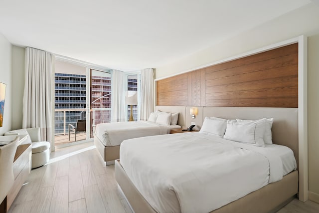 bedroom with access to outside, floor to ceiling windows, and light wood-type flooring