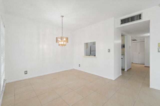 tiled empty room featuring an inviting chandelier