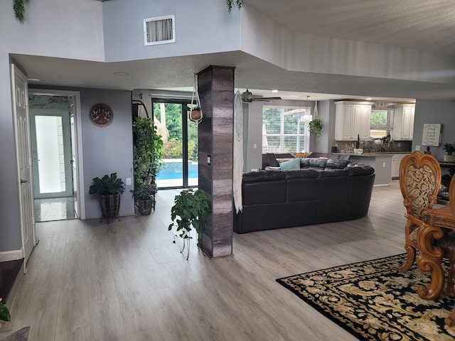 living room with light hardwood / wood-style floors, a high ceiling, and ceiling fan