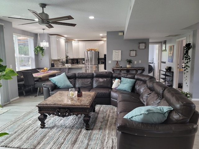 living room with light hardwood / wood-style flooring, washer / clothes dryer, a textured ceiling, and ceiling fan