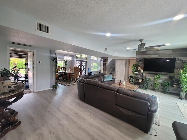 living room featuring ceiling fan, a textured ceiling, light hardwood / wood-style flooring, and a healthy amount of sunlight